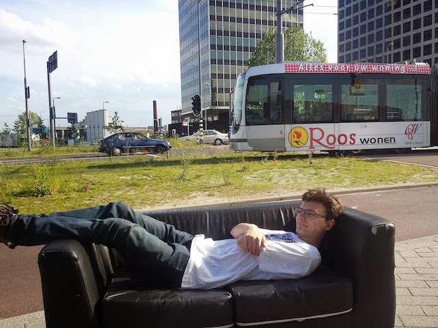 Couch with me on it put down on Marconiplein in Rotterdam. Tram is passing behind it.